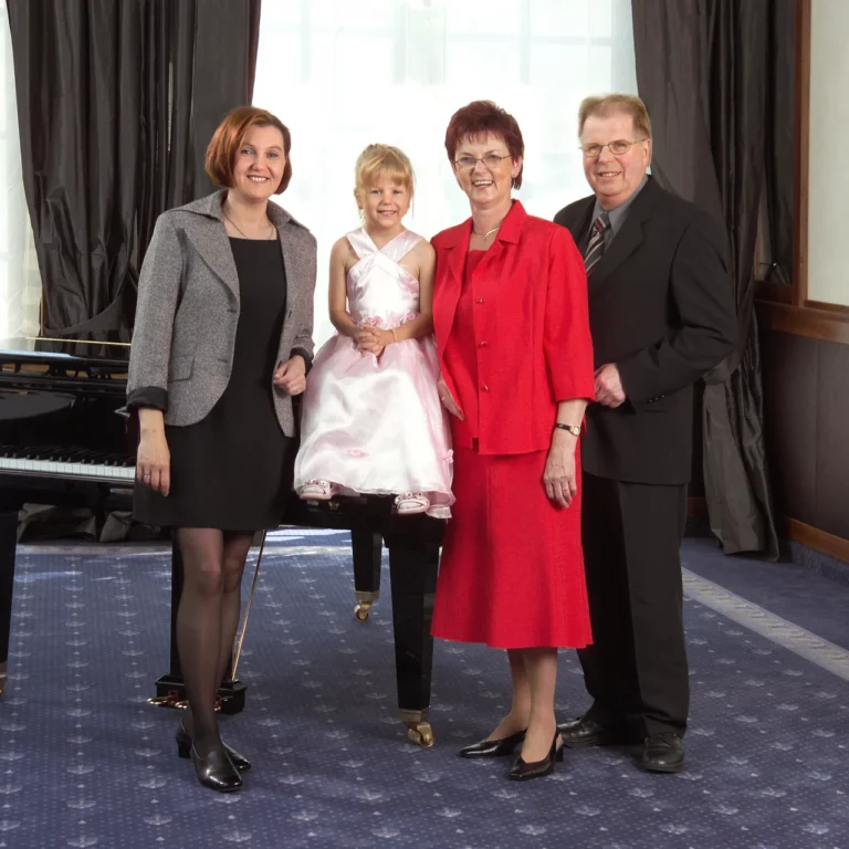 Familie Prescher vor einem Klavierfl&uuml;gel in einem gro&szlig;en mit Teppich ausgestattetem Raum